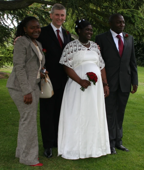 a bride with three grooms posing for a po on the grass
