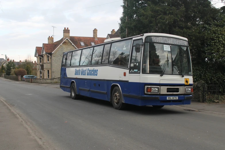 a blue and white bus drives down the road