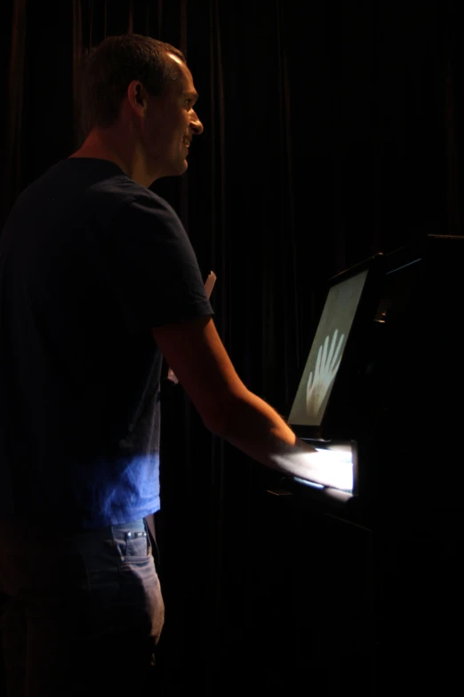 man in dark room with laptop illuminated by light