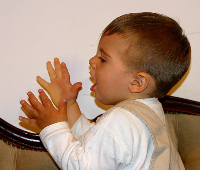 a little boy in a white shirt holding his hands out to an air