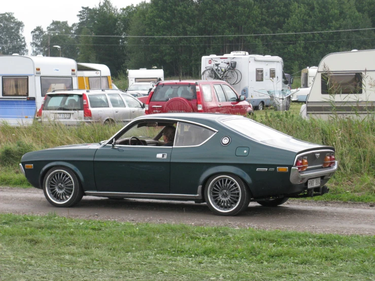 the car is parked in the parking lot near many camping vehicles