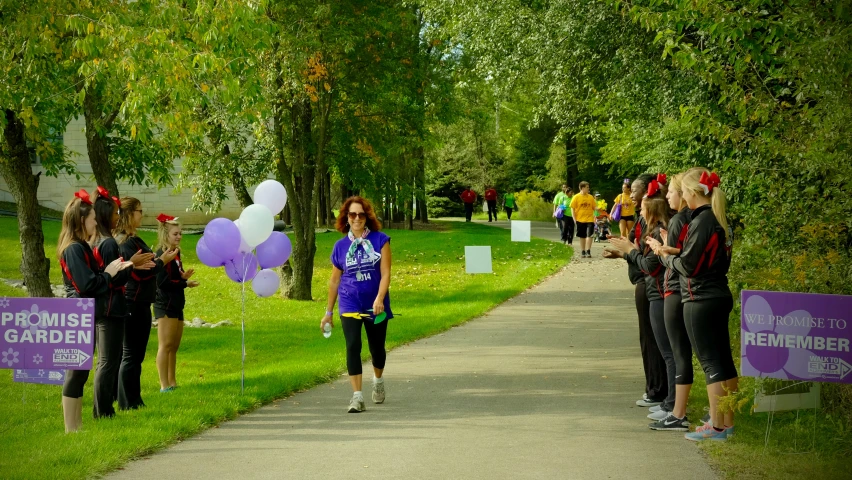 a woman walking down a path while holding up a purple banner