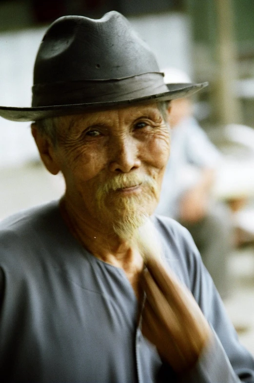 old man wearing a hat with one hand on his tie