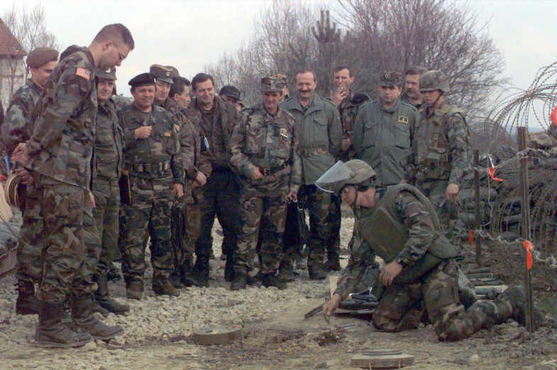 several men in military attire are watching a man