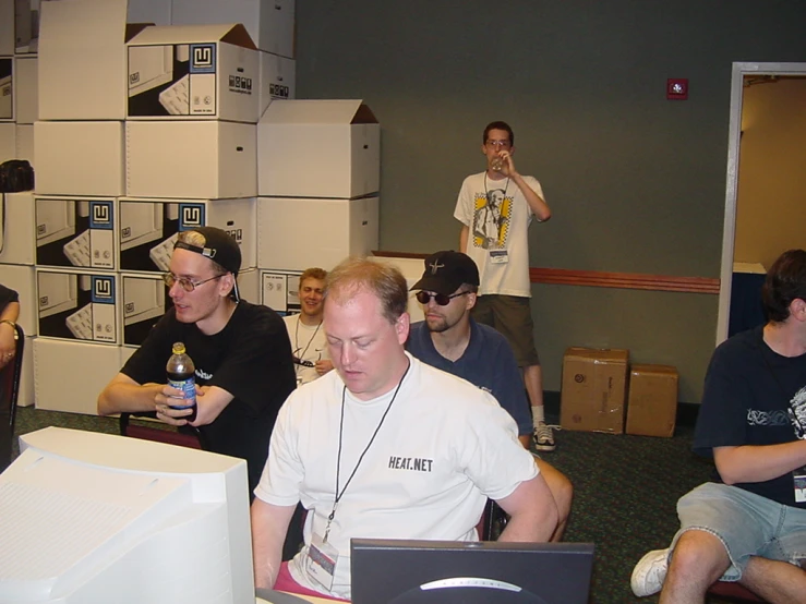 men in a office with some computer screens and a laptop