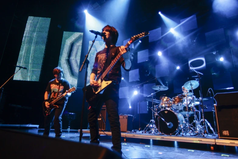 some young men are performing on stage while their guitar player is on the side