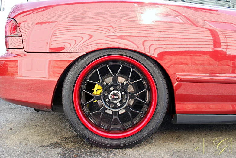 a red car with some black tires in a parking lot
