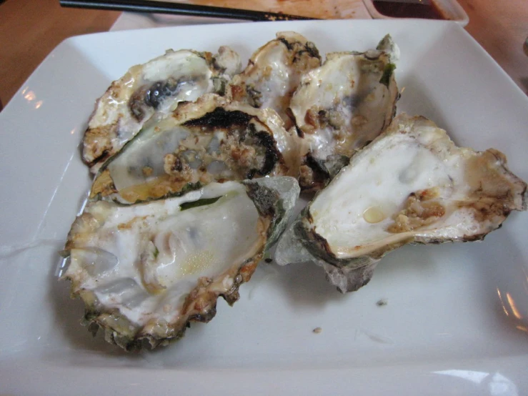 four oysters on a plate with a wooden background