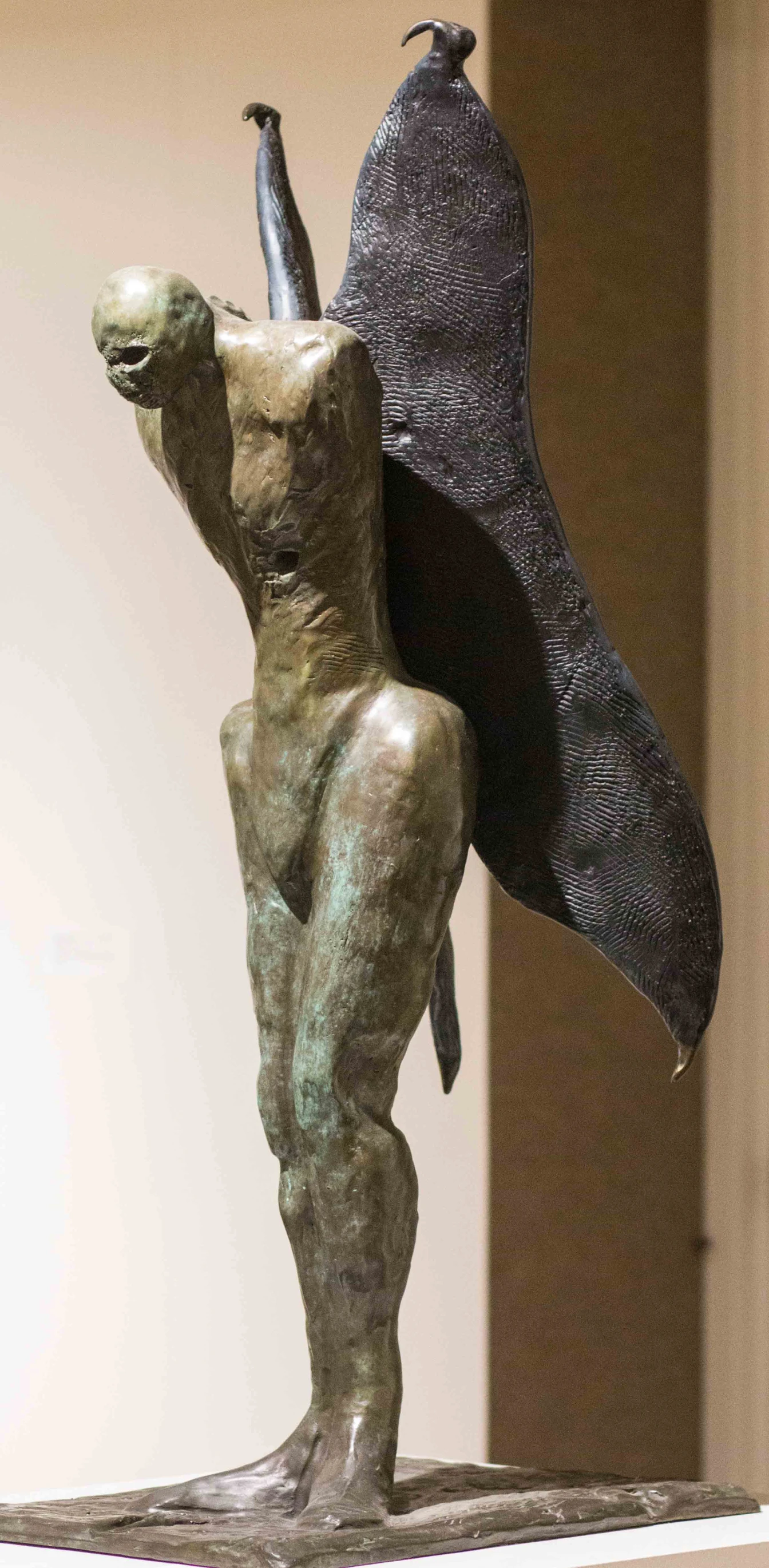 a sculpture of a man in a cape standing next to the wall