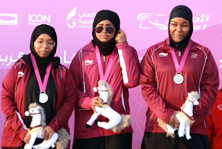 four women holding stuffed animals and medals