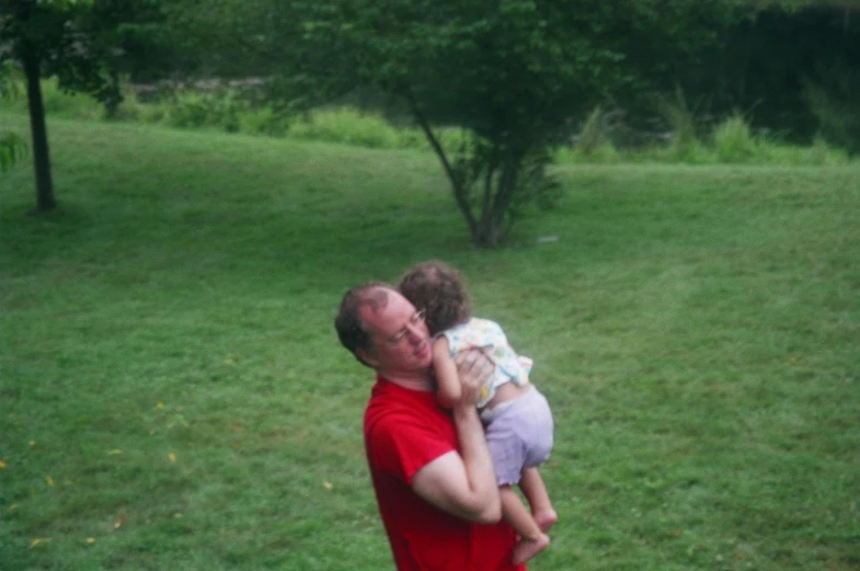 a father is holding his little daughter in the park