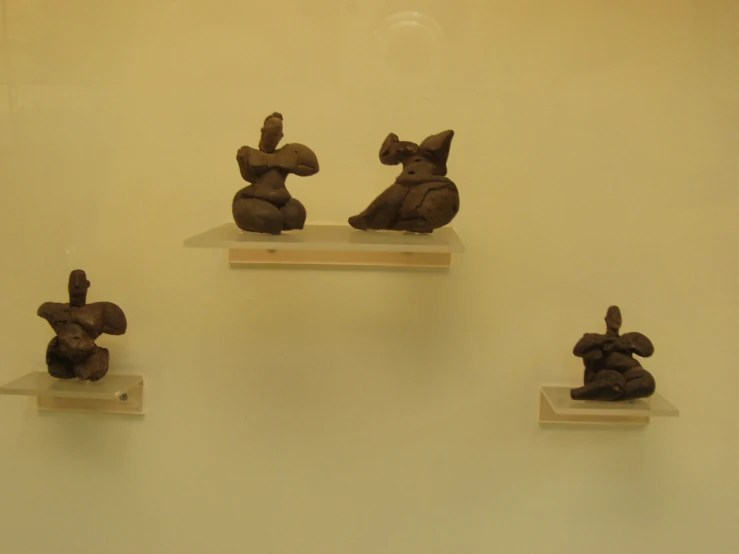 four figurines that look like elephants sitting in front of a wall