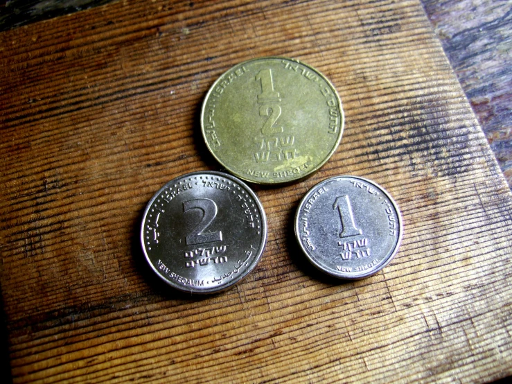 three coins are sitting on a wooden table