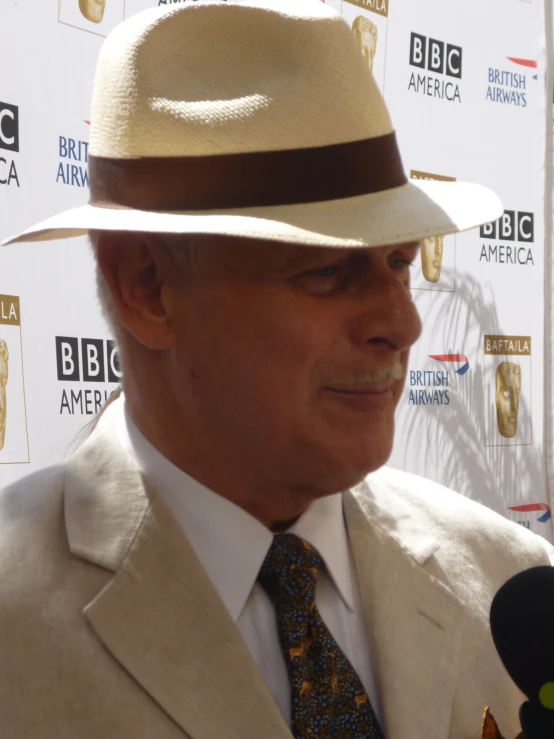 an older man in a hat talking into a microphone