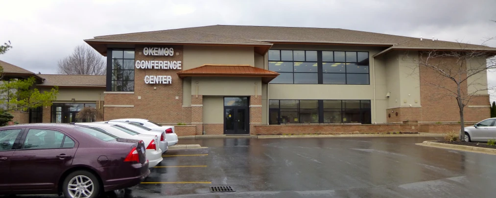 the front view of an office building with cars parked outside