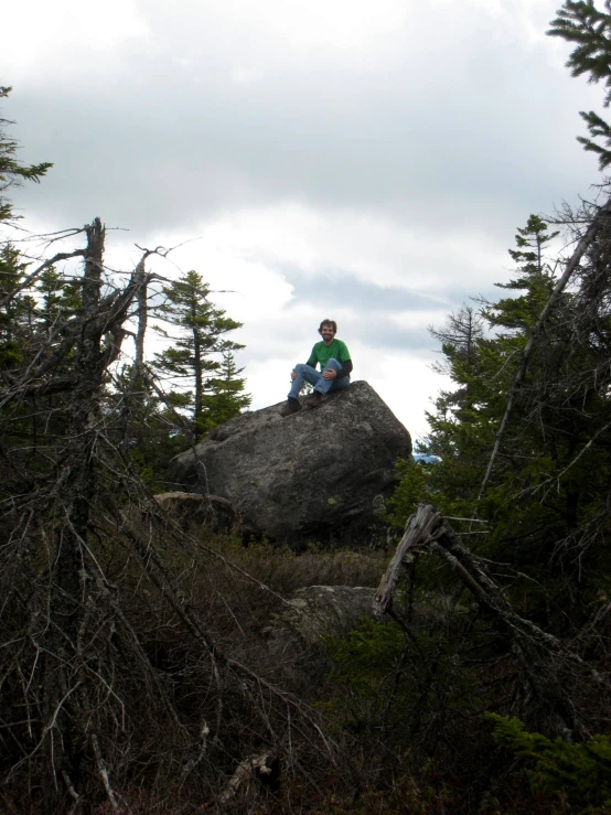 a man sitting on a rock between some trees