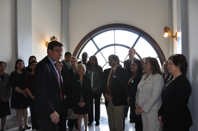 the men and women stand in front of a large circle window