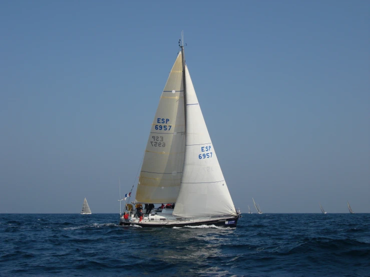 three sailboats racing in the blue ocean