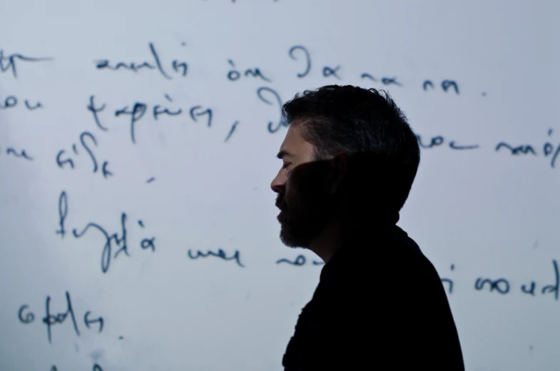 man standing in front of writing on the white wall