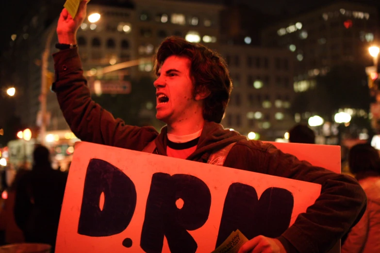 a man holding a protest sign that says drm