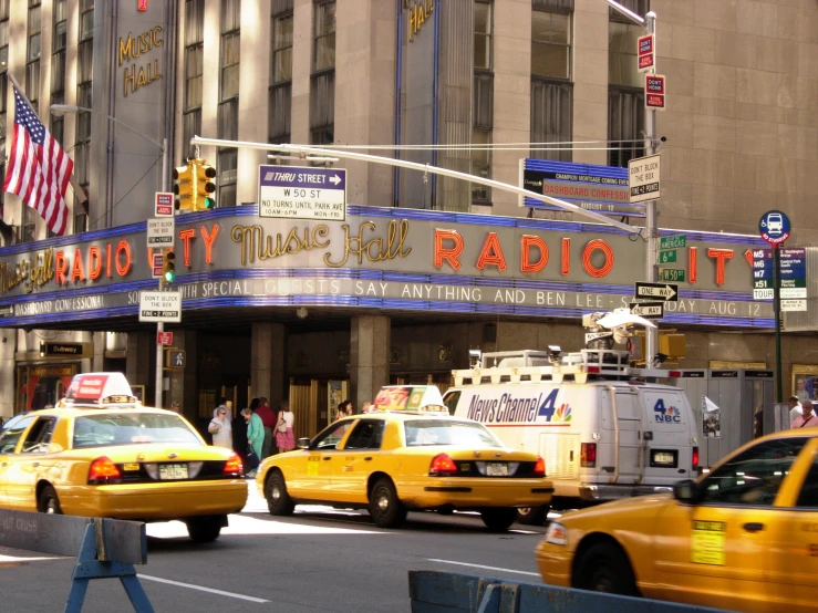 taxi cabs in front of an outdoor radio city movie theatre