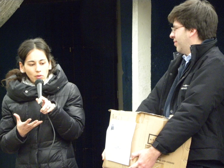 a man is standing with a microphone and talks to a woman