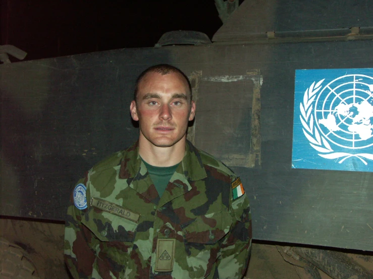 a soldier standing in front of a sign with a logo on it