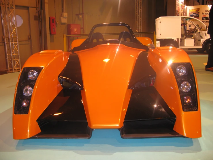 an orange sport car sitting in front of a machine