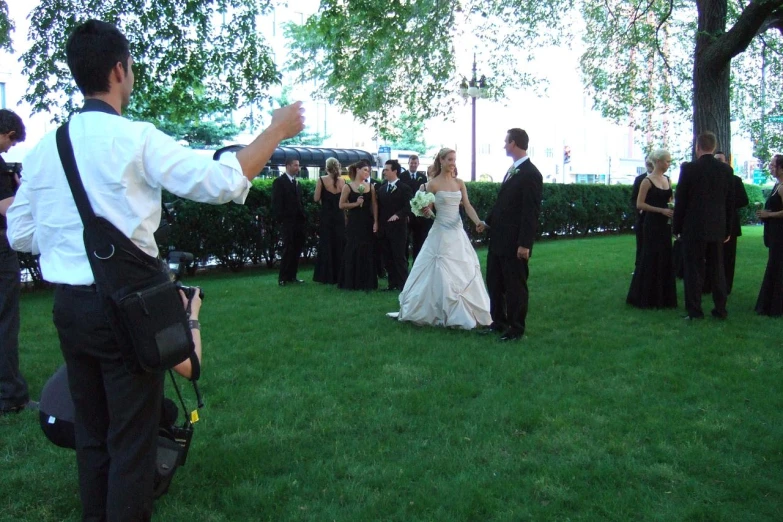 a wedding party takes pos in the grass while people watch