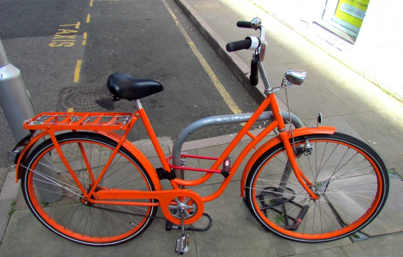 orange bicycle parked on a city sidewalk