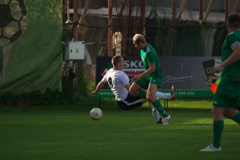 three men in uniforms are playing soccer on a field