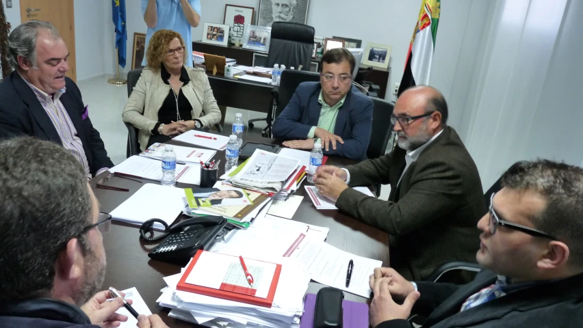 a group of men sitting at a table with paperwork