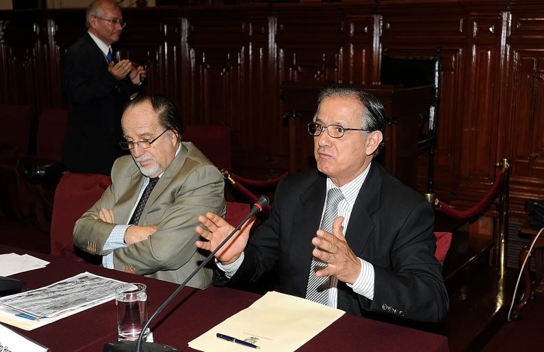 two men in suits sitting at a table during a meeting