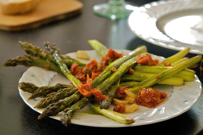 plate of green asparagus with red sauce on it