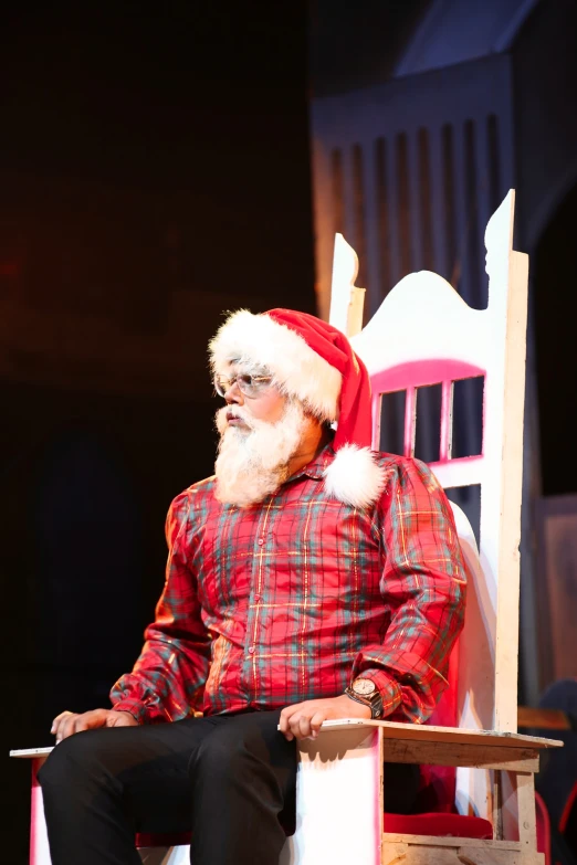 man sitting in chair with santa hat on on stage