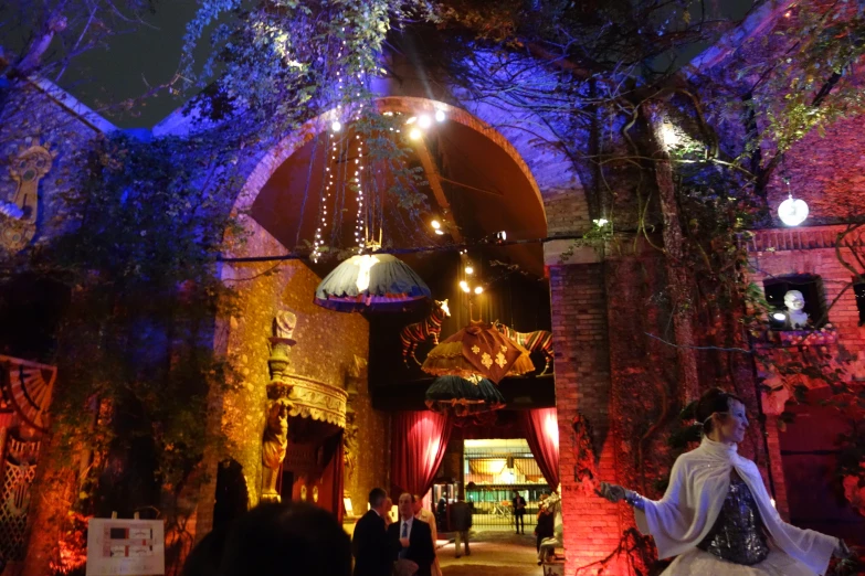 an archway with some lights around it and people walking under