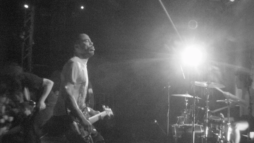 a man standing in front of a stage while someone plays guitar