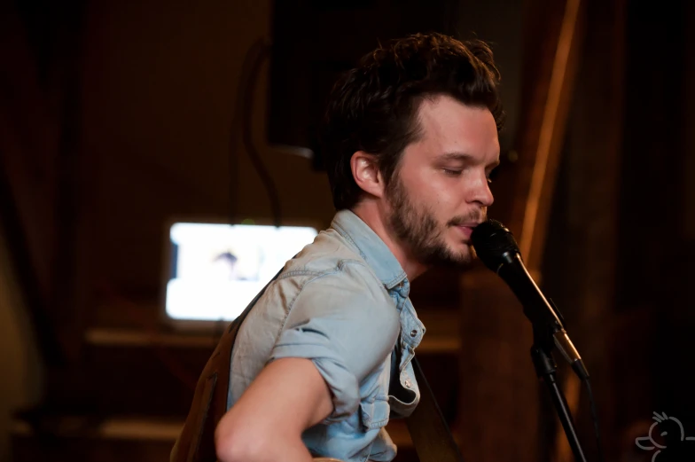 a man in blue shirt singing into a microphone