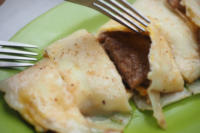 a green plate topped with meat and cheese