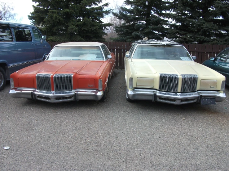 two vintage cars parked in front of a garage