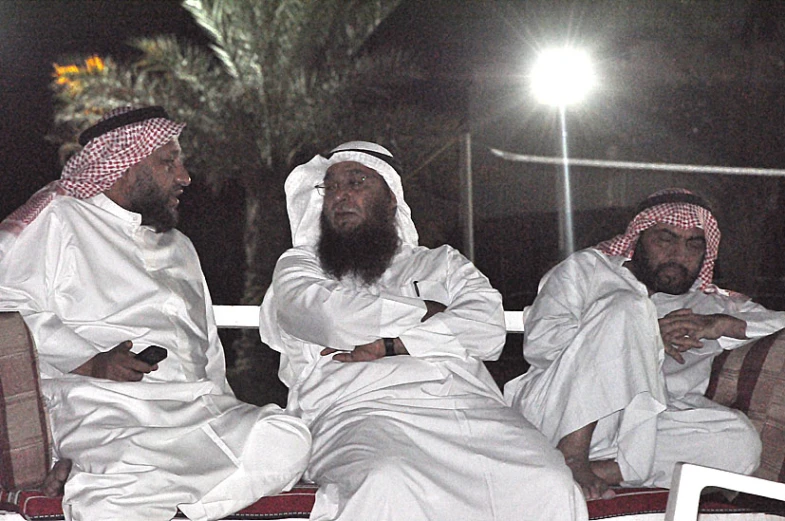 three men in white sitting down with their arms crossed