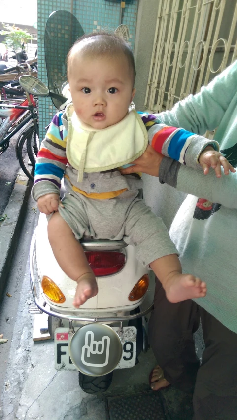 a young toddler sitting on top of an old scooter