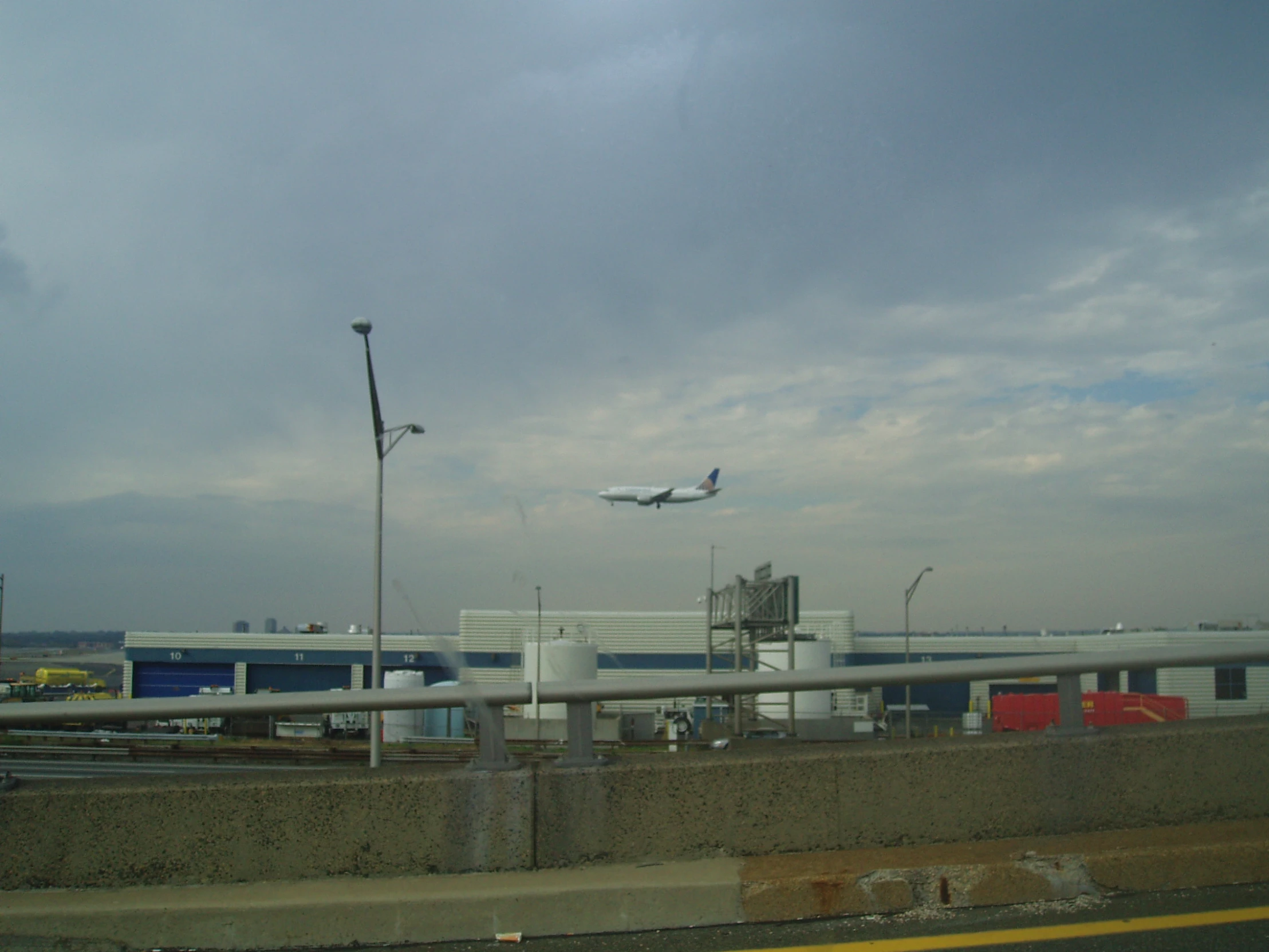 an airplane flies over the airport with smoke coming from it