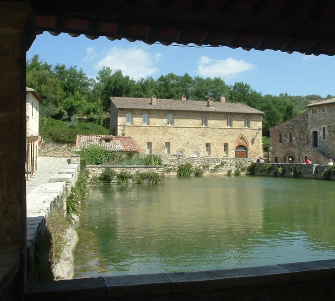 a building on the river with green water and people looking through the front windows