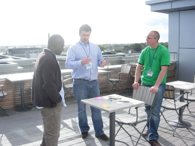 a group of people standing around table and chairs on top of a building