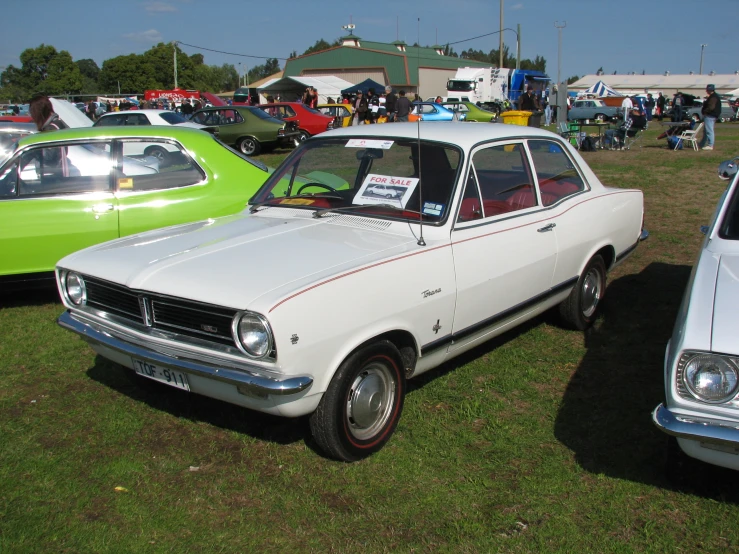 three old model cars are on display at an outdoor event