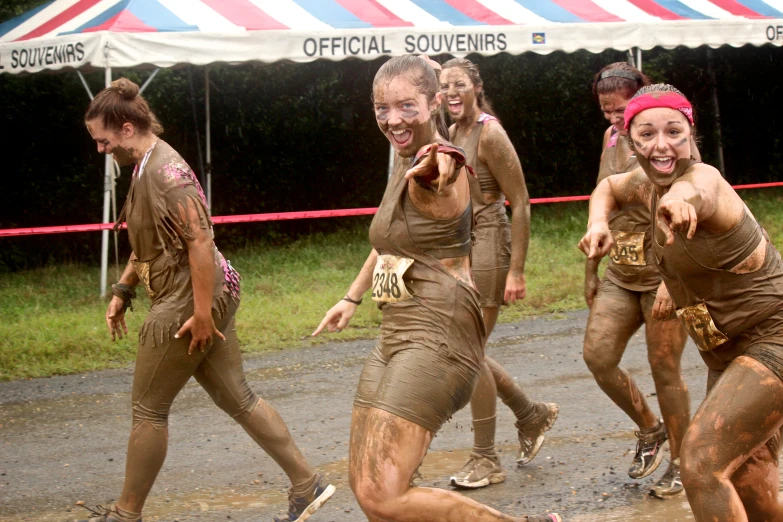 a group of young people running in muddy mud