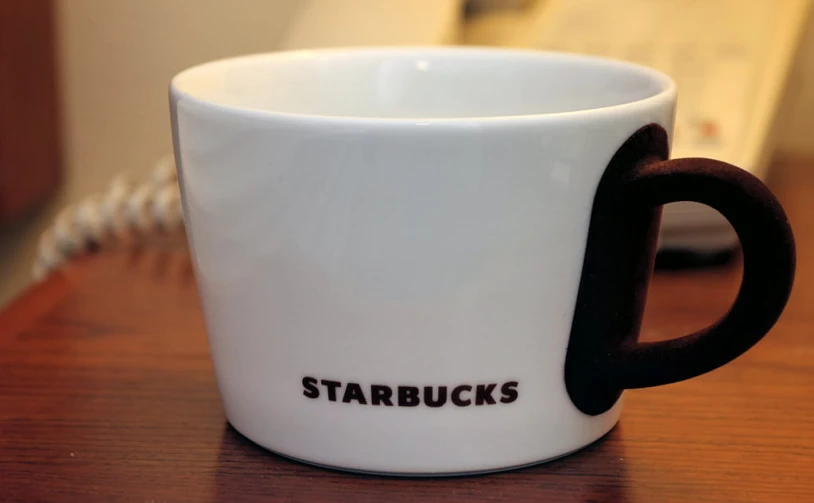 a white coffee cup with a handle saying starbucks's