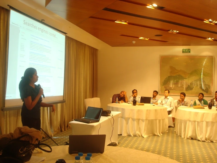 a meeting room full of people and an individual with a large white table