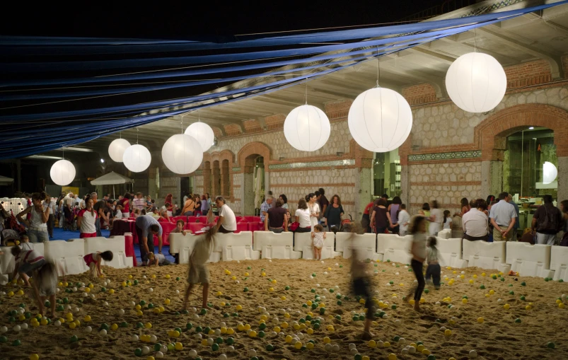 a crowd of people standing around a room filled with paper lanterns